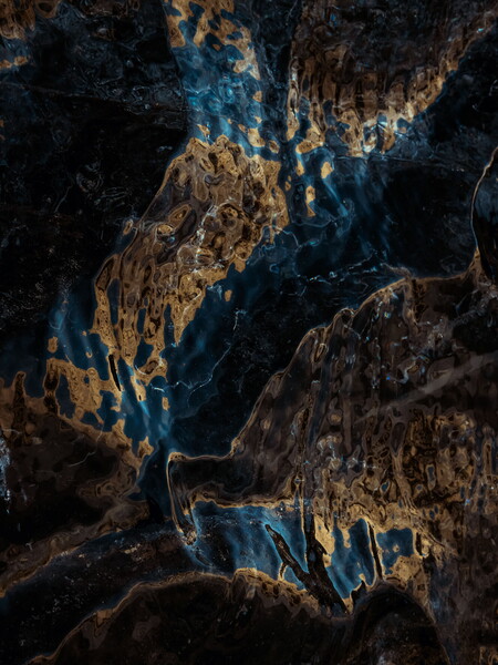 Abstract photograph of golden sunlight reflecting on dark glacier in Iceland