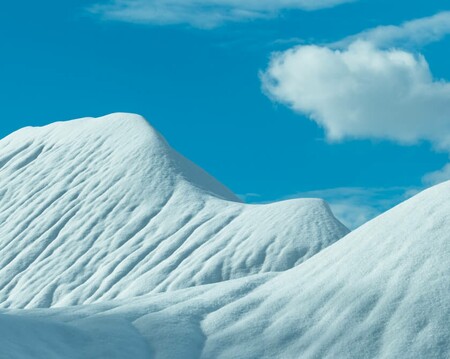 Abstract winter landscape with snow covered hills and a blue sky with soft clouds