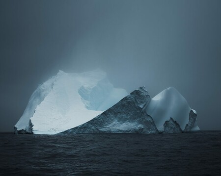 Majestic iceberg surrounded by ominous skies and fog in Antarctica with penguin colony