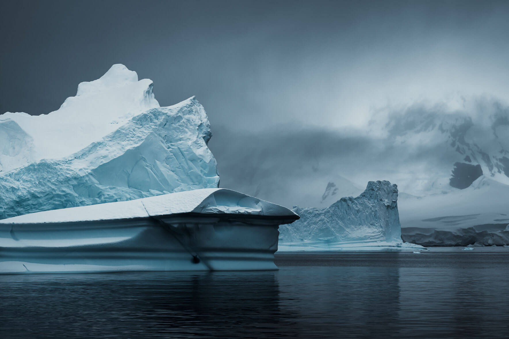 Antarctic iceberg in dark and dramatic colors with mountains