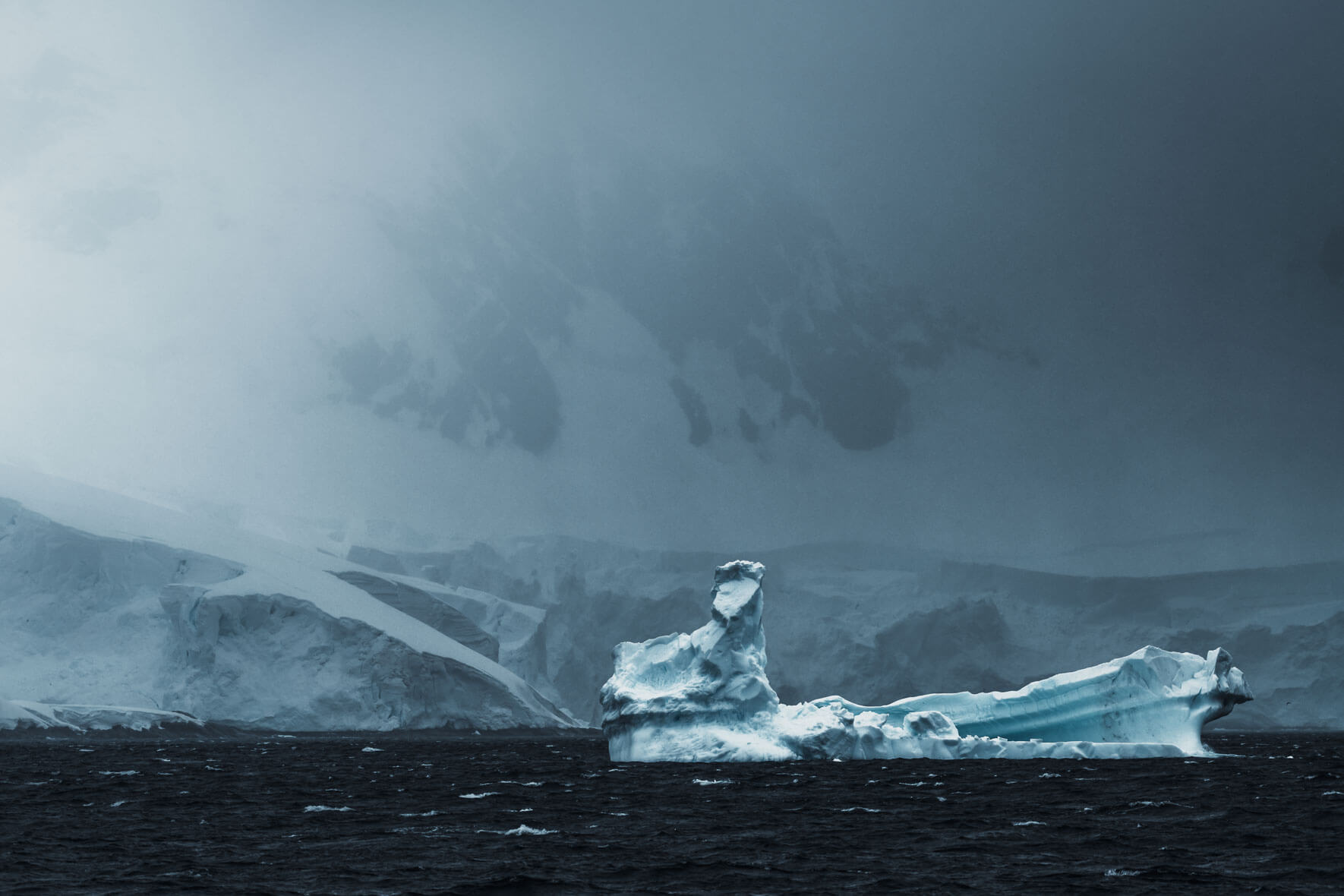 Iceberg broken off from the Antarctic Peninsula with dark clouds