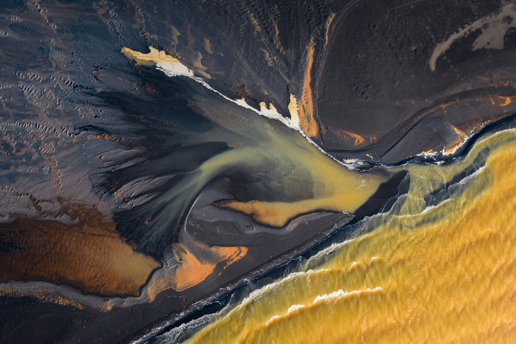 Abstract yellow lake with dark shoreline and small waves in Iceland