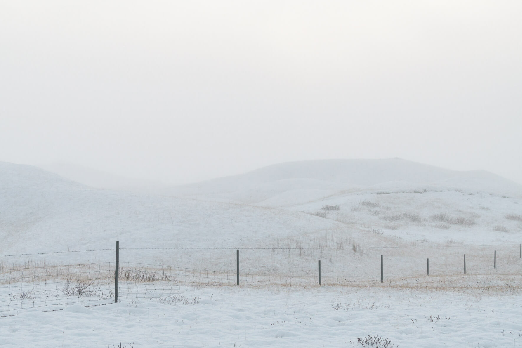 Minimalist scene with snow covered hill and fence in winter