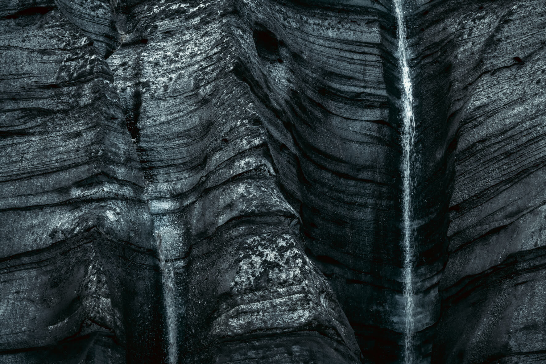 Dark ice of Kötlujökull glacier near Vík í Mýrdal in Iceland with small waterfalls