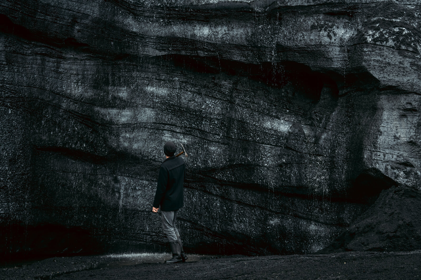 Sand and ash covered glacier ice of Kötlujökull (Katla ice cave) with man standing in foreground