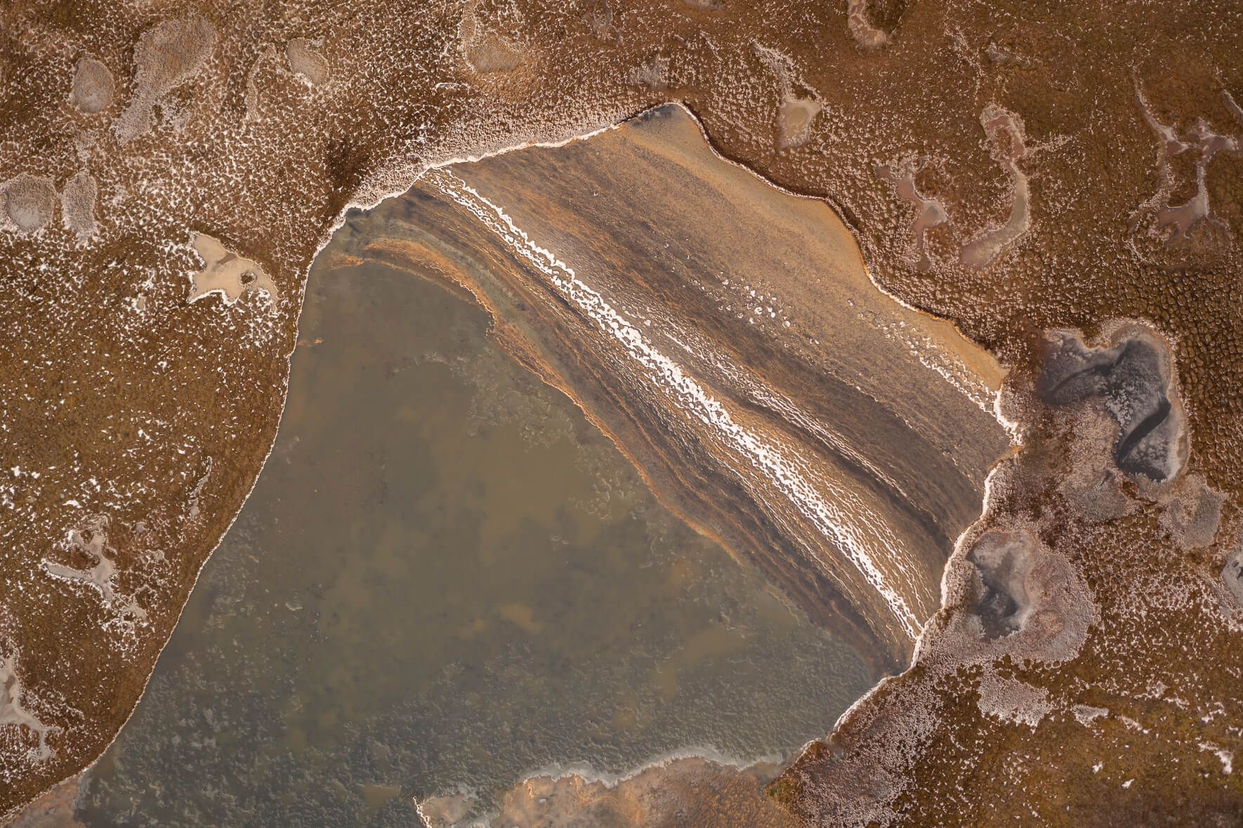 Colorful frozen pond on Jökuldalsheiði plateau in eastern Iceland after a storm