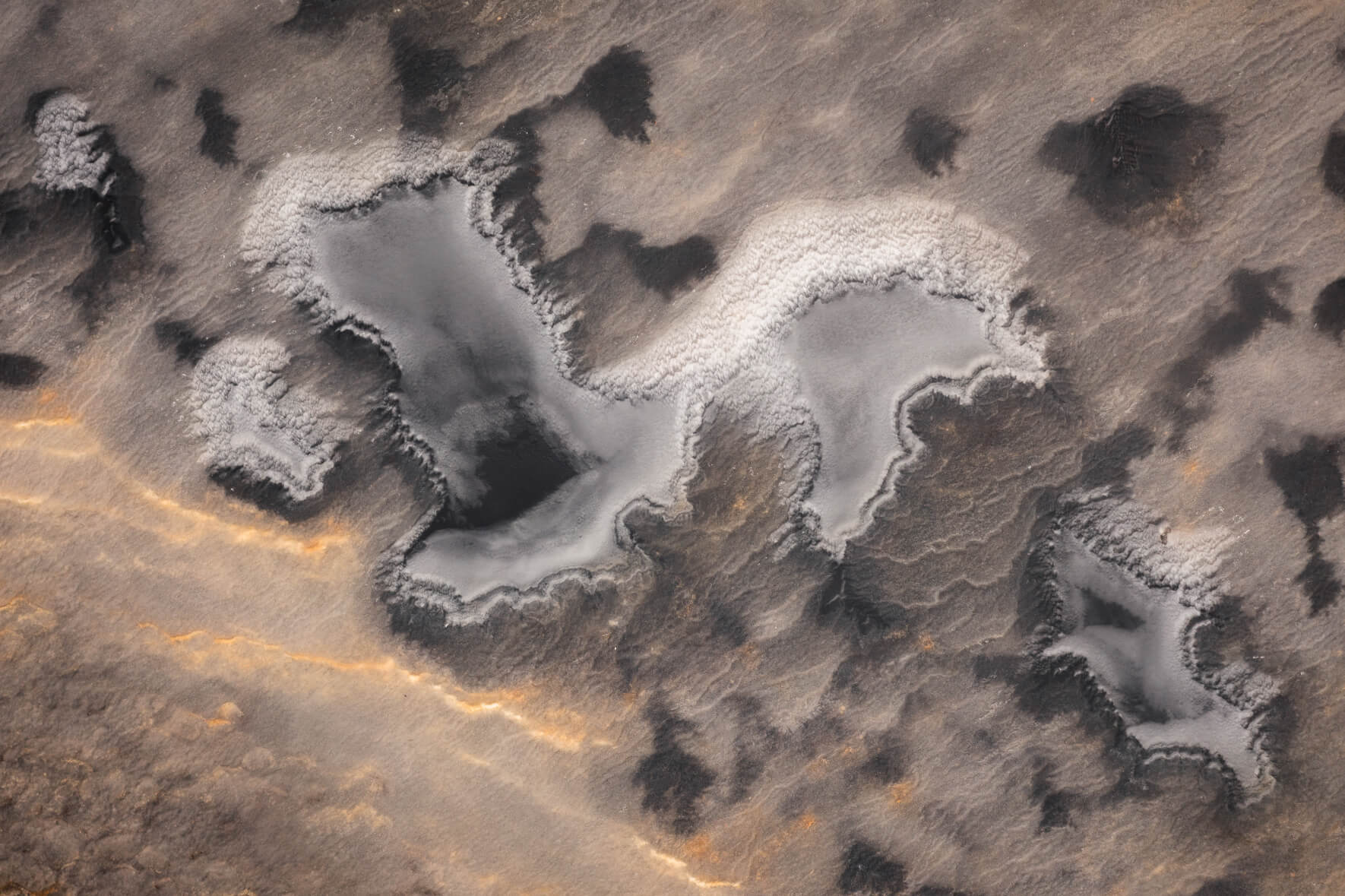 Abstract aerial photograph of frozen pond with ice and sand in eastern Iceland