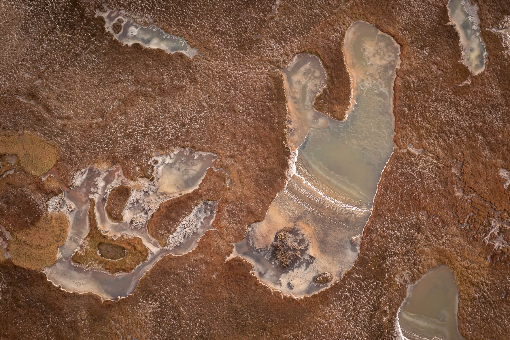 Aerial view of colorful frozen ponds on Jökuldalsheiði plateau in eastern Iceland