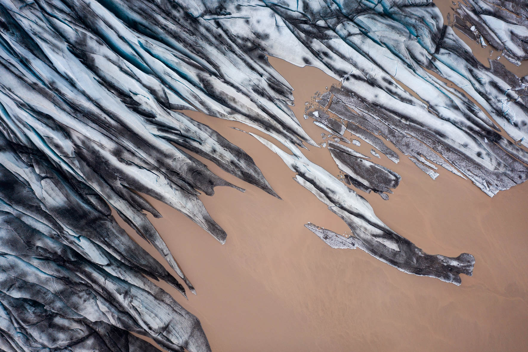 Aerial view of glacier with brown surrounding water