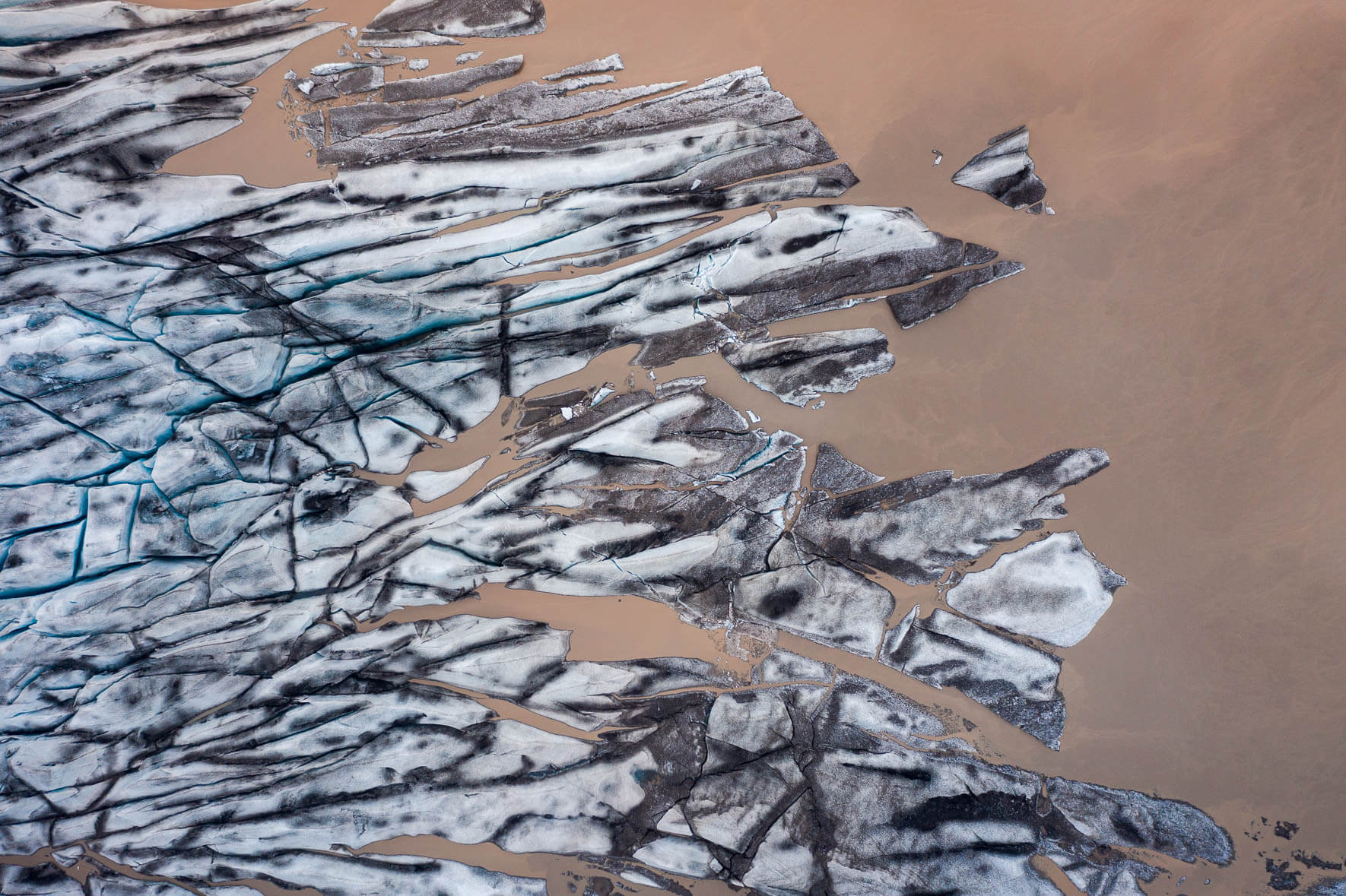 Aerial view of Fláajökull glacier in Iceland with glacial lake and brown ice water