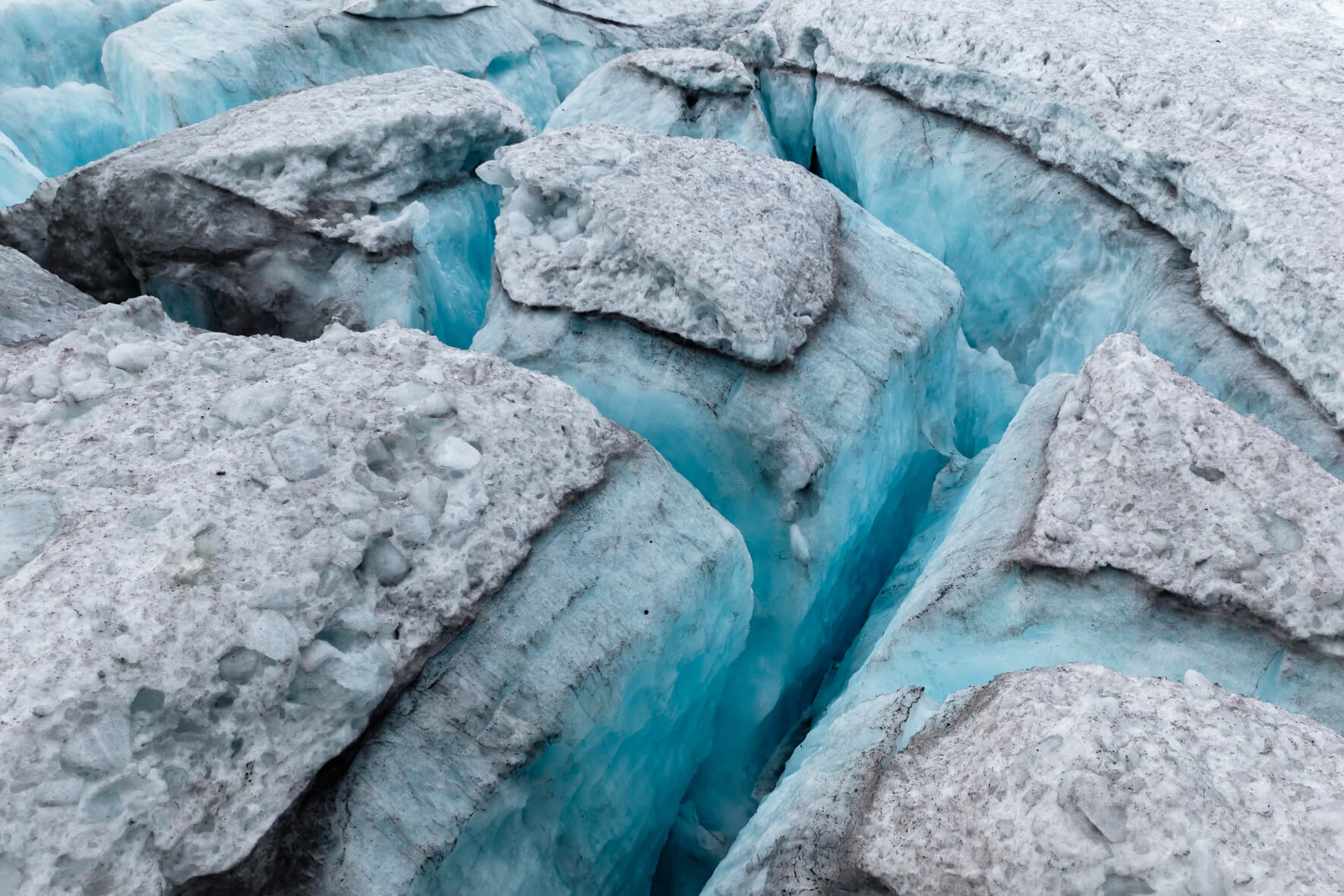 Aerial view of a snow-covered glacier in Norway with deep crevasses and blue glacier ice