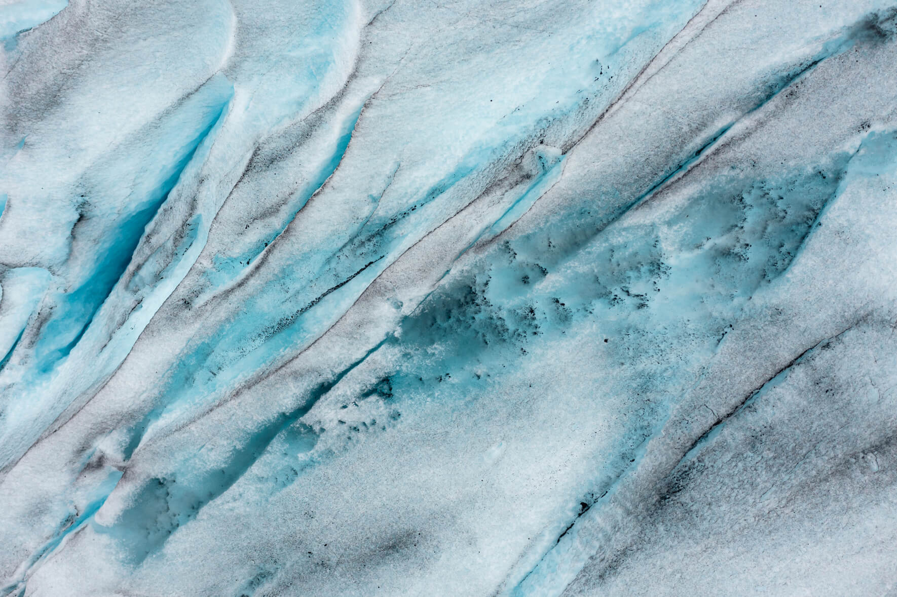 Meltwater lakes with sand and rocks on a frozen lake in Southern Norway in early summer