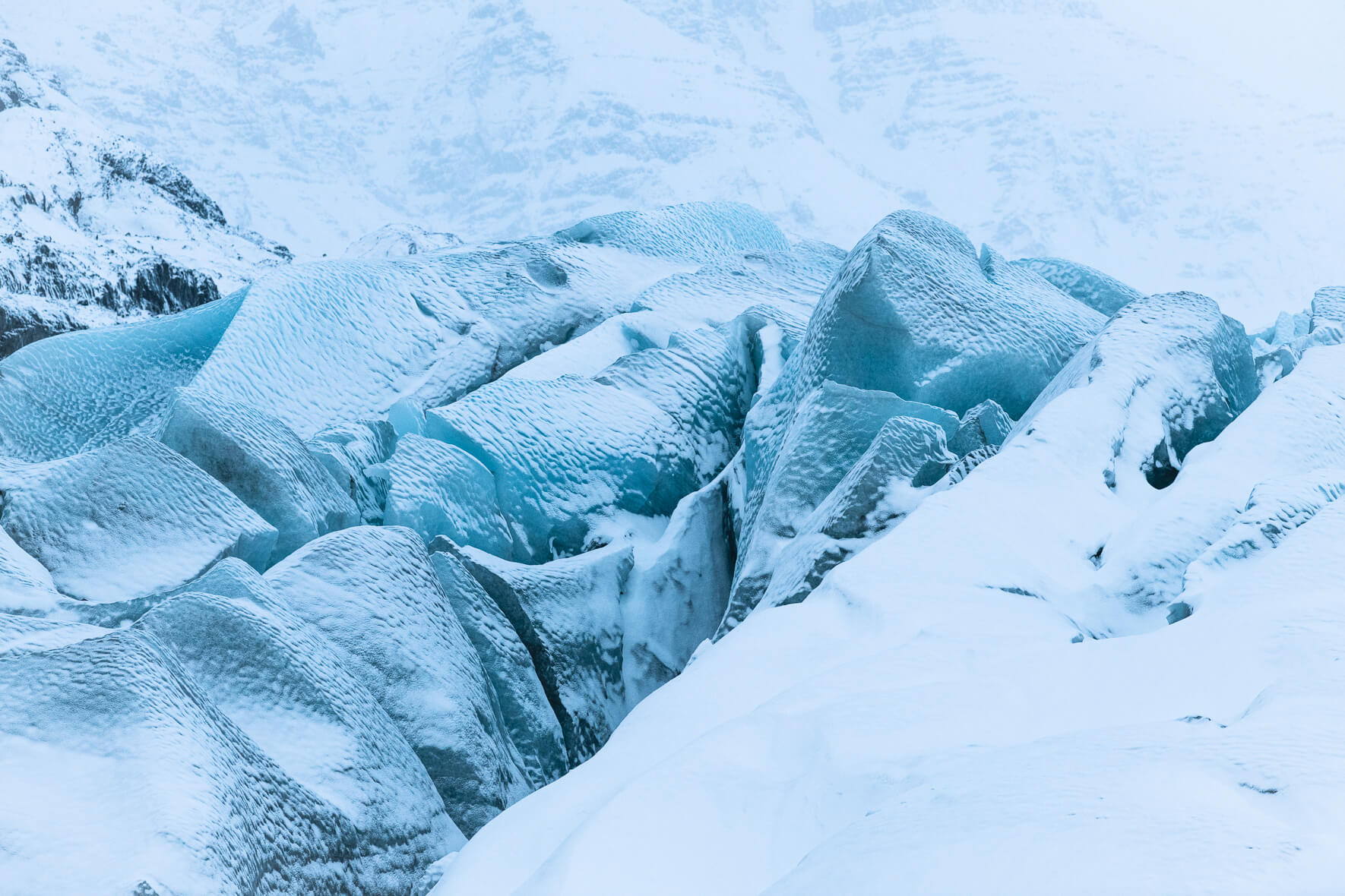 Svínafellsjökull glacier in Iceland after heavy snow shower with blue glacier ice