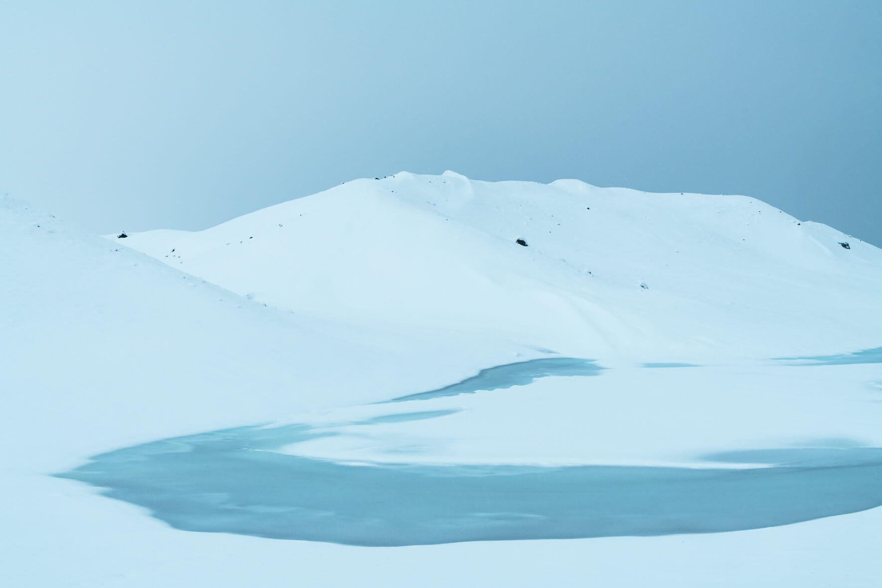 Minimalist winter landscape with snowy hills and frozen river in Iceland