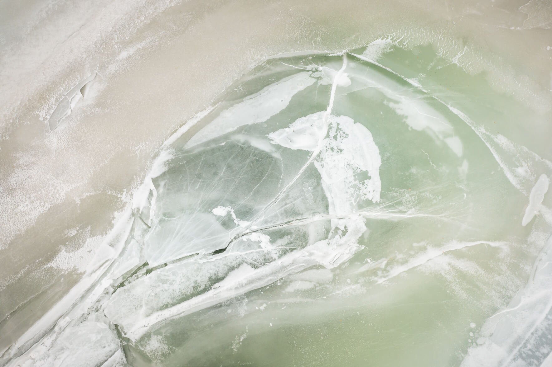 Ice of the frozen Åraksfjorden lake with a greenish tint due to algae