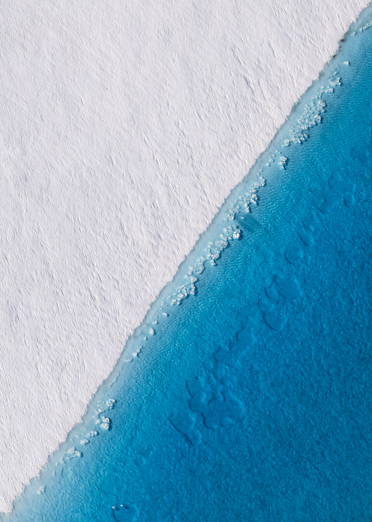 Deep blue meltwater lake on Columbia Glacier with ice floes, captured from a small plane