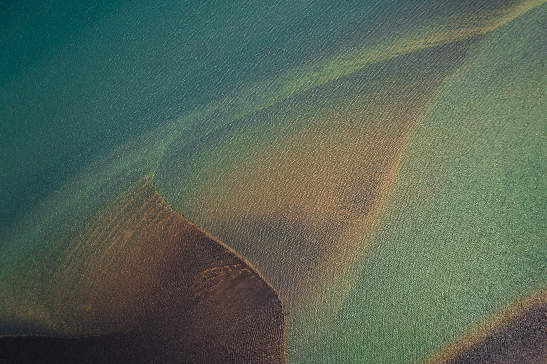 Abstract aerial view of a glacial river in Iceland with sandbank and water with small ripples