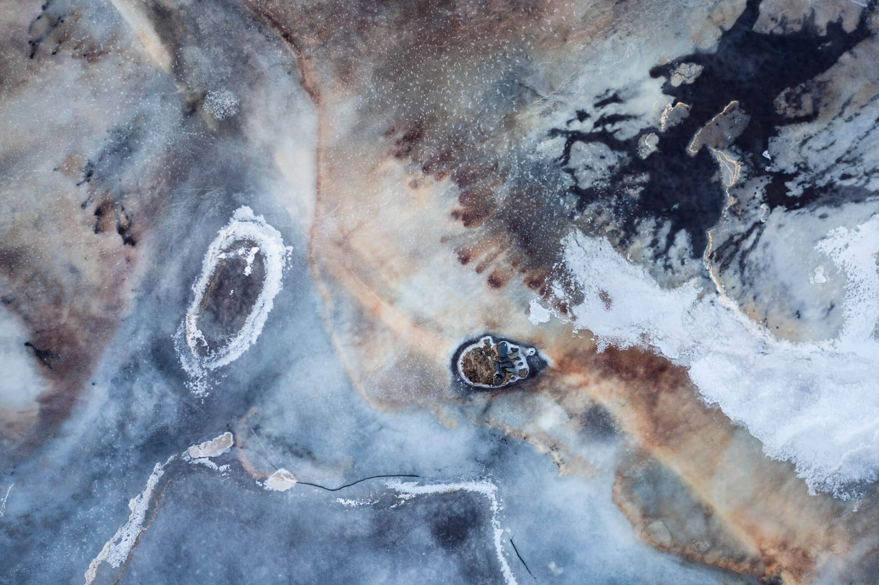 Aerial view of Iceland’s frozen marshlands, showcasing intricate ice patterns and organic textures