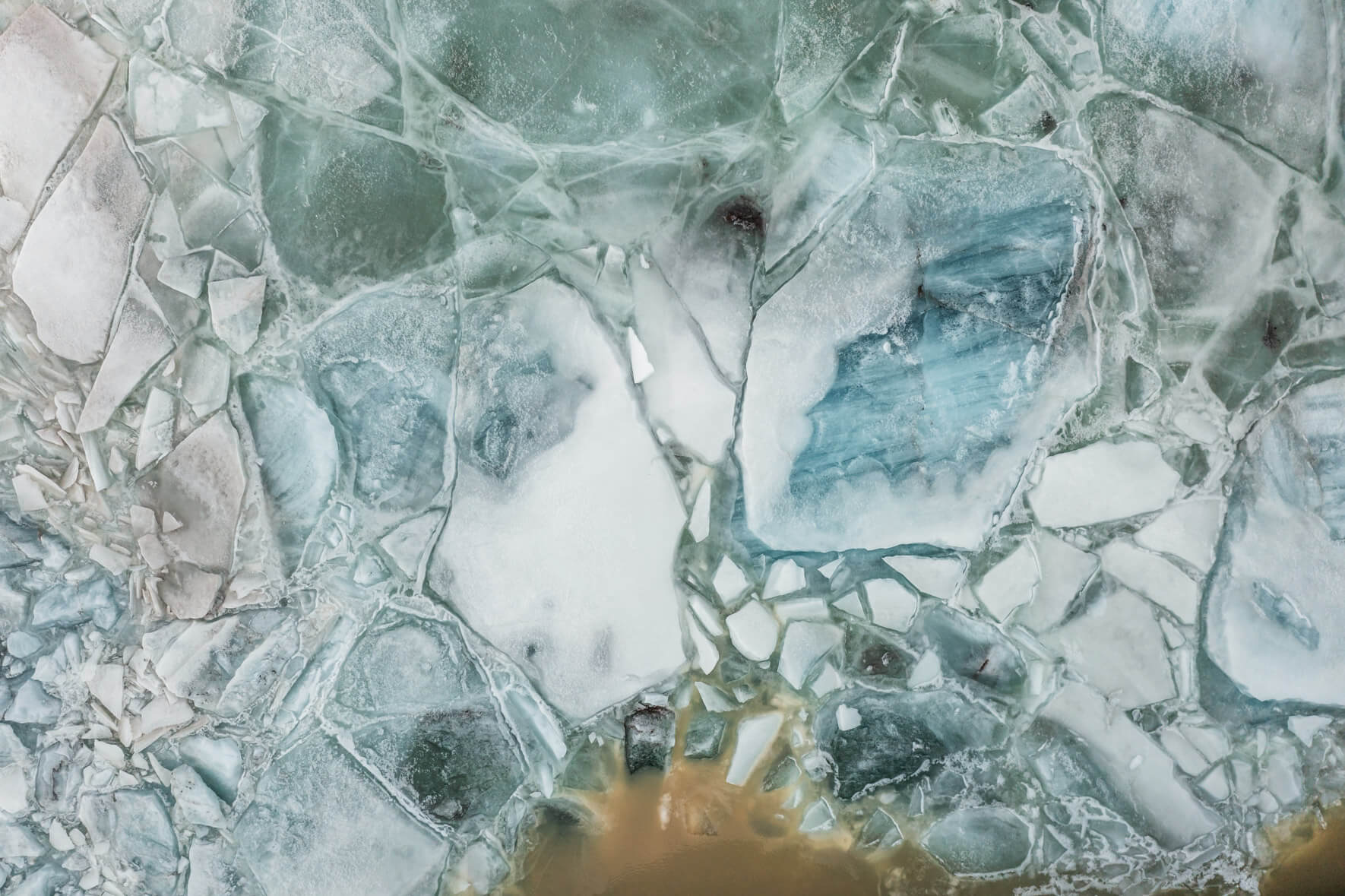 Drone perspective of Svínafellslón in winter, where fractured ice and floating icebergs create striking patterns