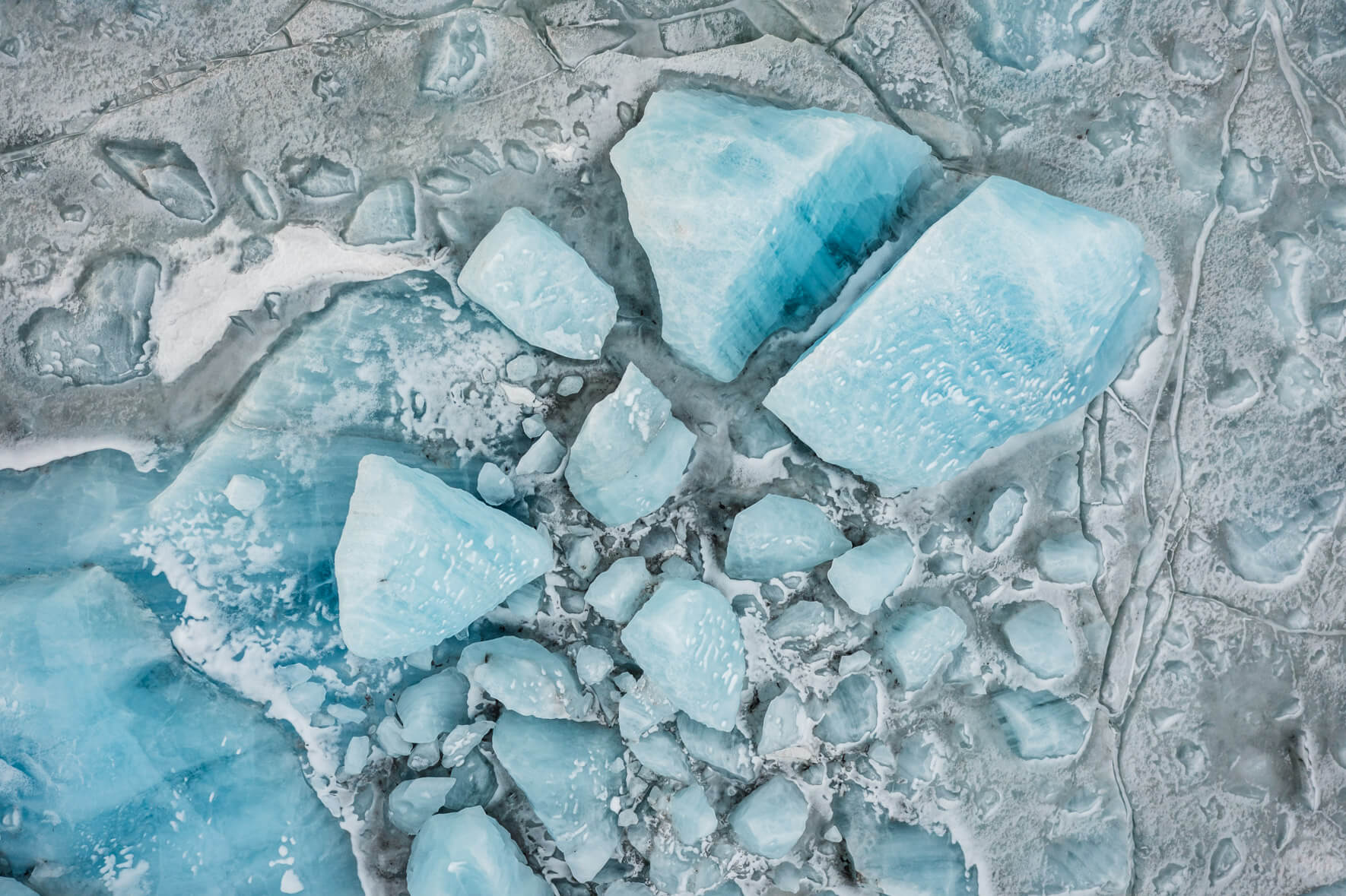 Glacial lagoon Svínafellslón in Iceland from above with massive blue icebergs frozen in the ice