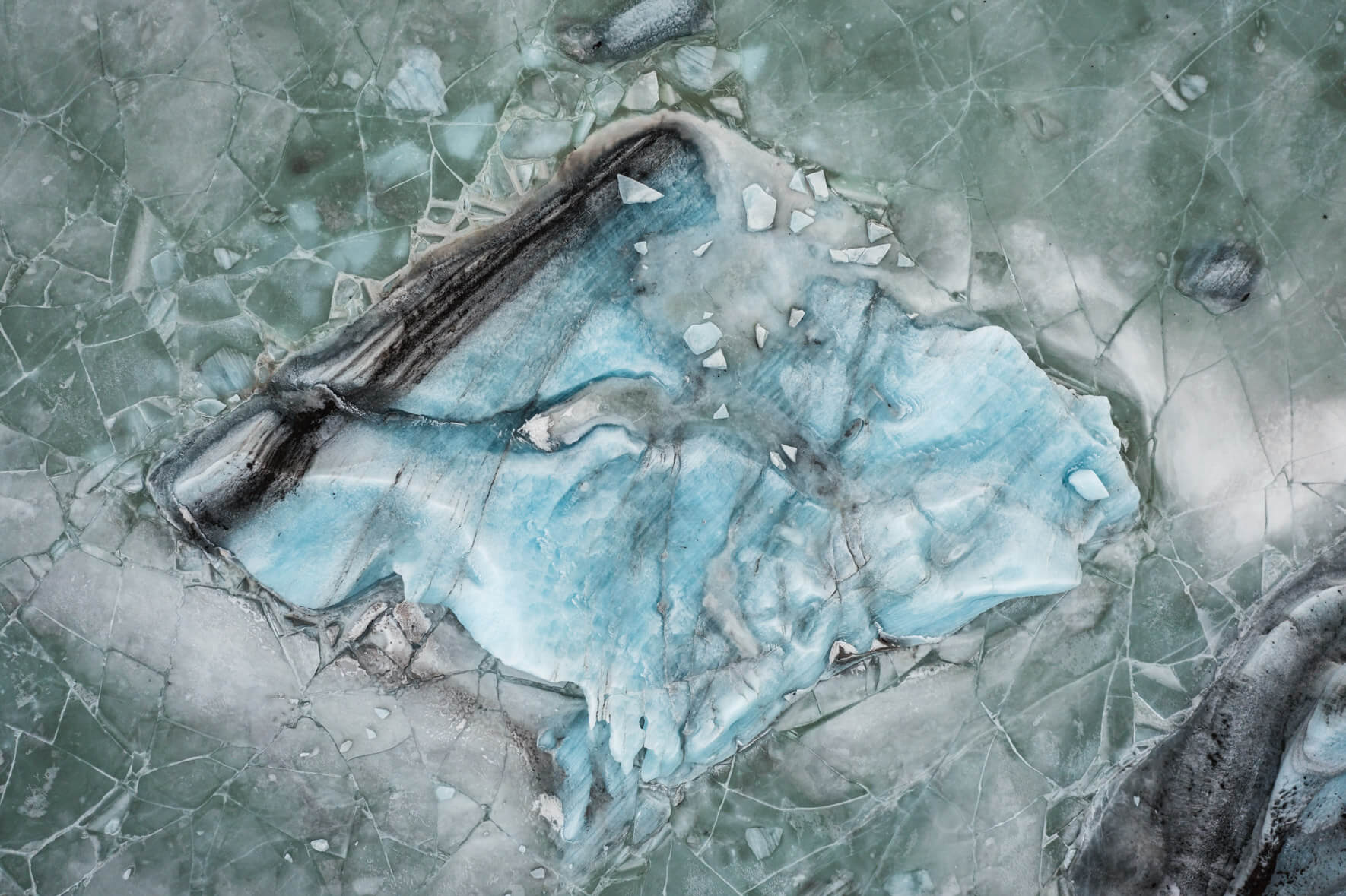 Glacial lagoon Svínafellslón in Iceland from above with massive iceberg frozen in the ice