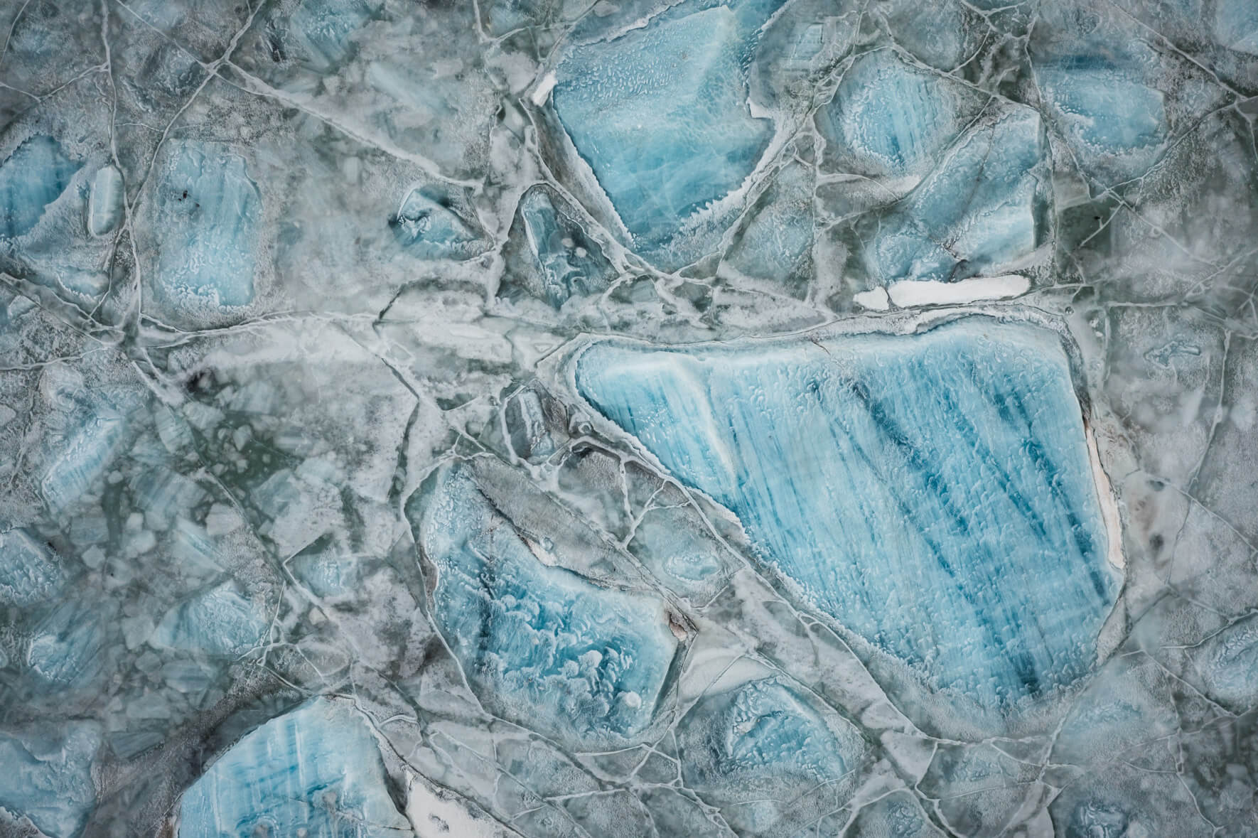 Glacial lagoon Svínafellslón in Iceland from above with massive icebergs frozen in the ice