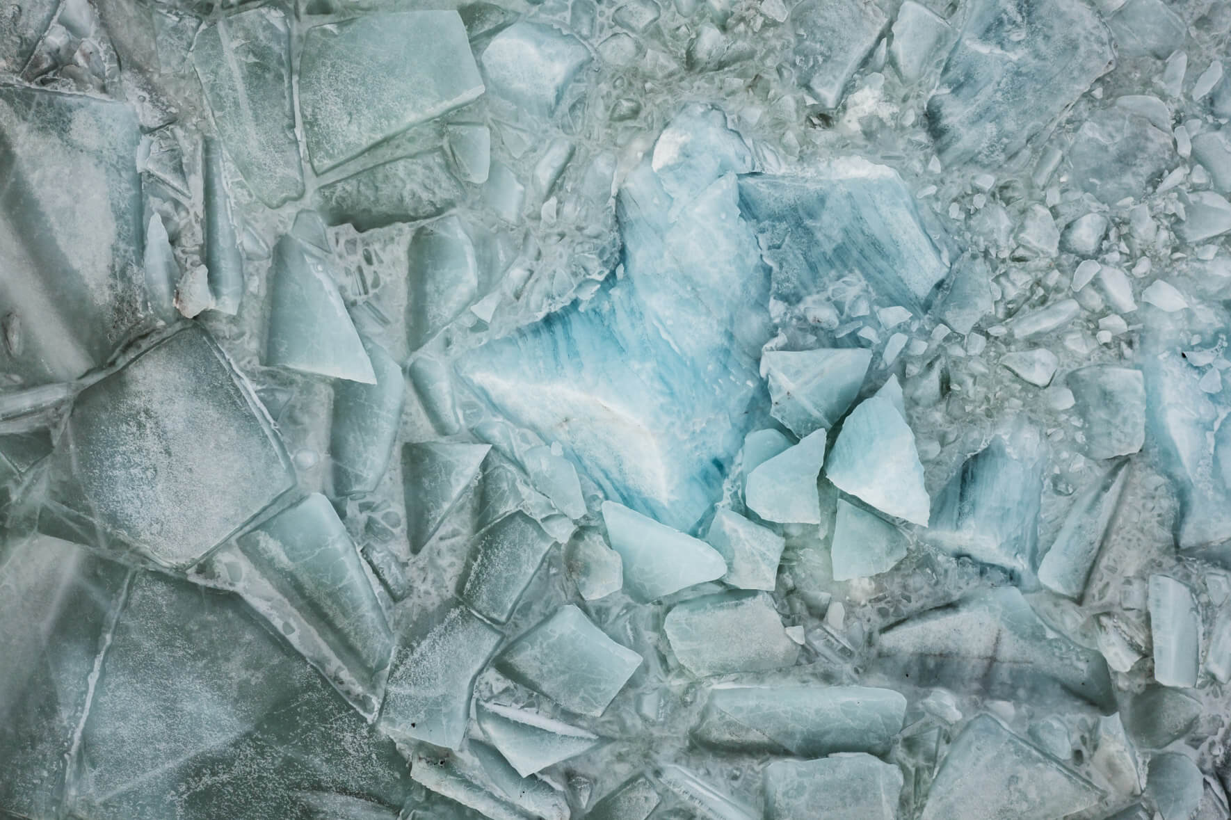 Aerial view of Svínafellslón lagoon in Iceland with a broken ice surface and numerous icebergs