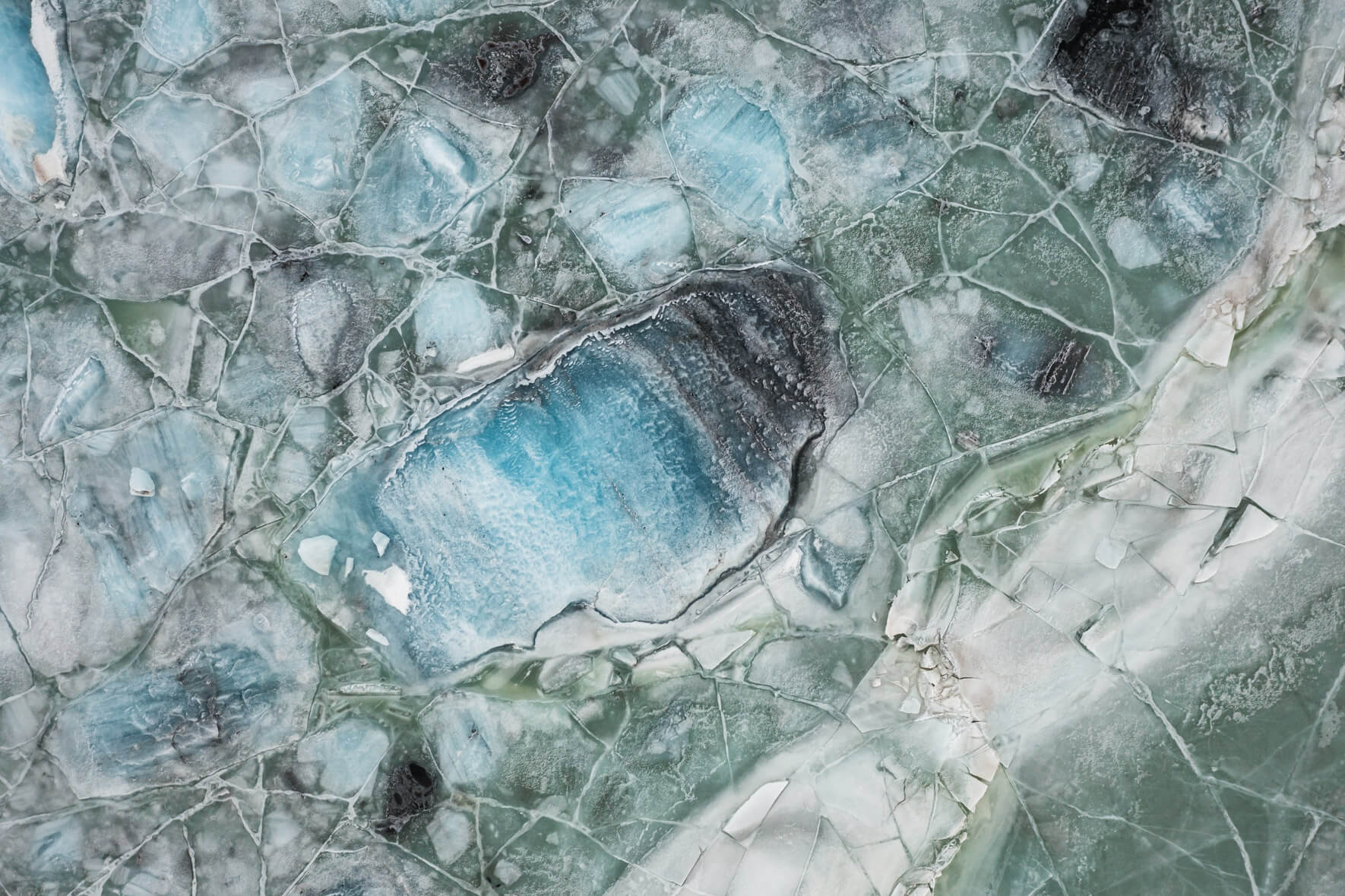 Bird's eye view of the Svínafellslón lagoon in Iceland with a broken ice surface and icebergs