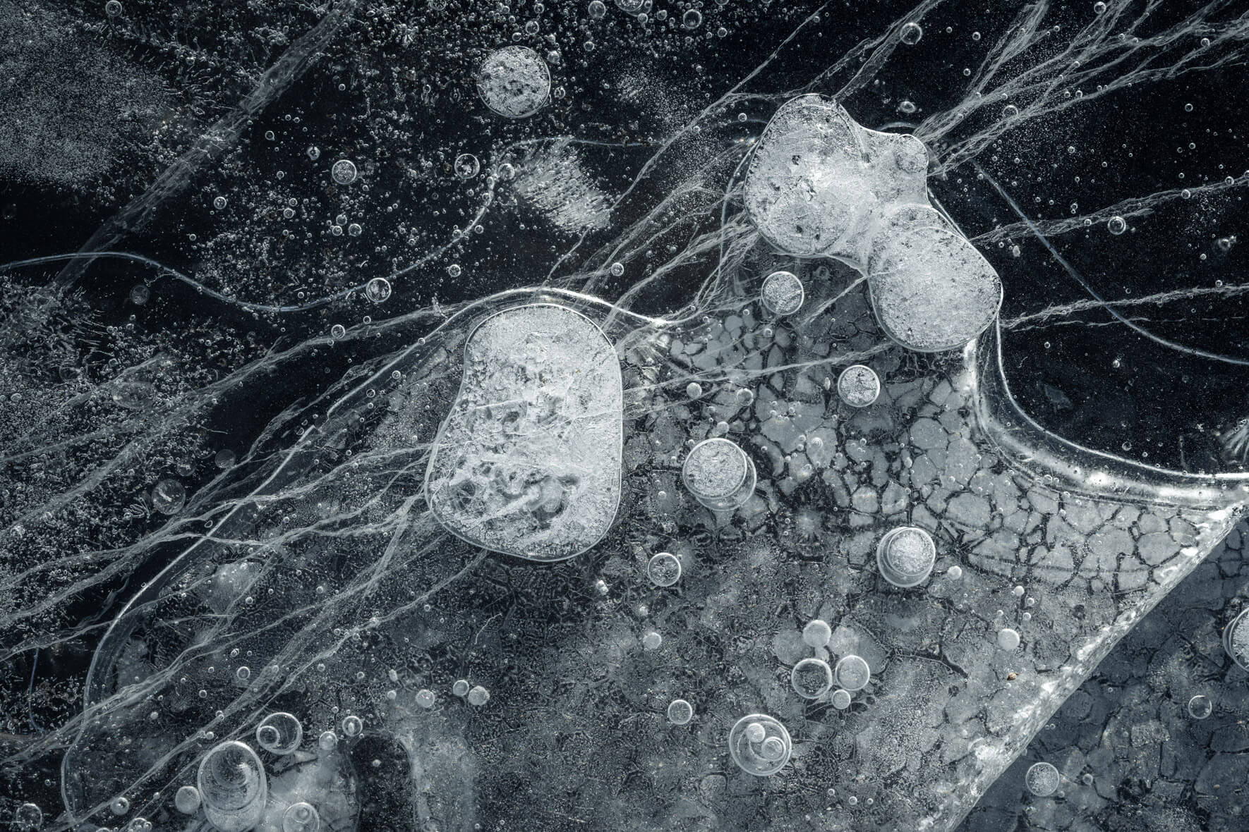 Macro photography of frozen gas bubbles in dark ice, highlighting nature’s formations