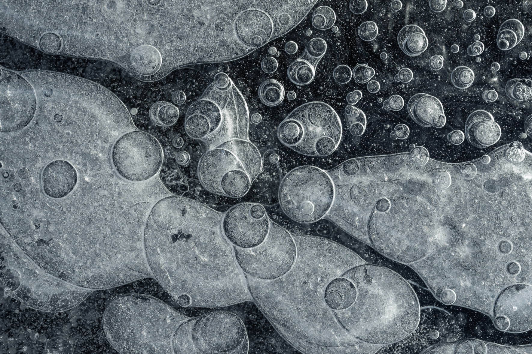 Macro close-up of frozen methane and oxygen bubbles in black ice in Iceland