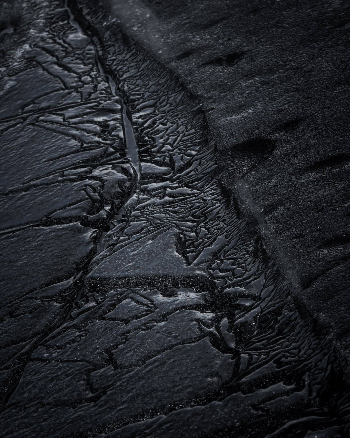 Textured dark ice formations on the lake shore in Iceland, revealing fine crystalline structures