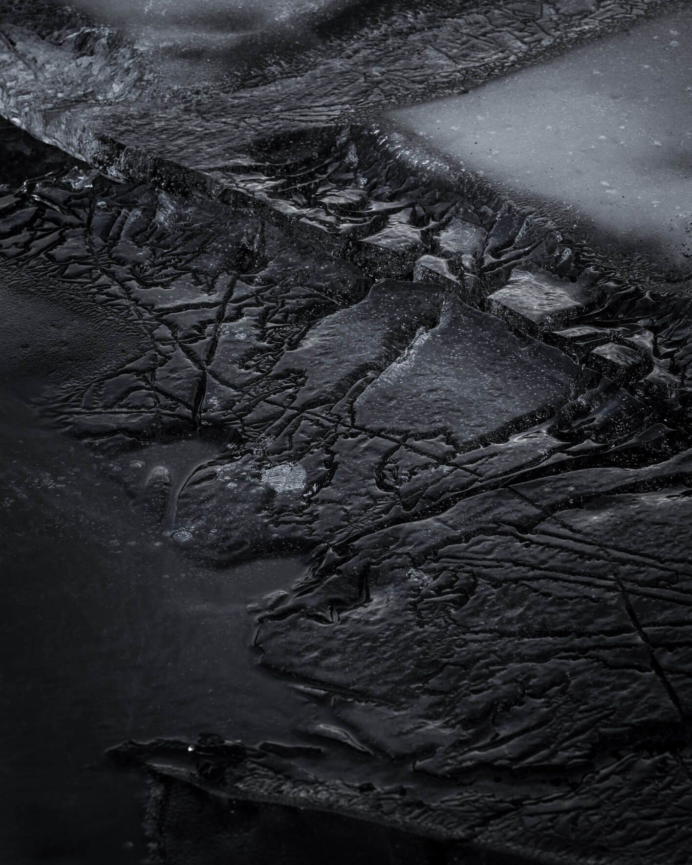 Close-up of layered dark ice at Lake Kleifarvatn, highlighting natural formations and textures