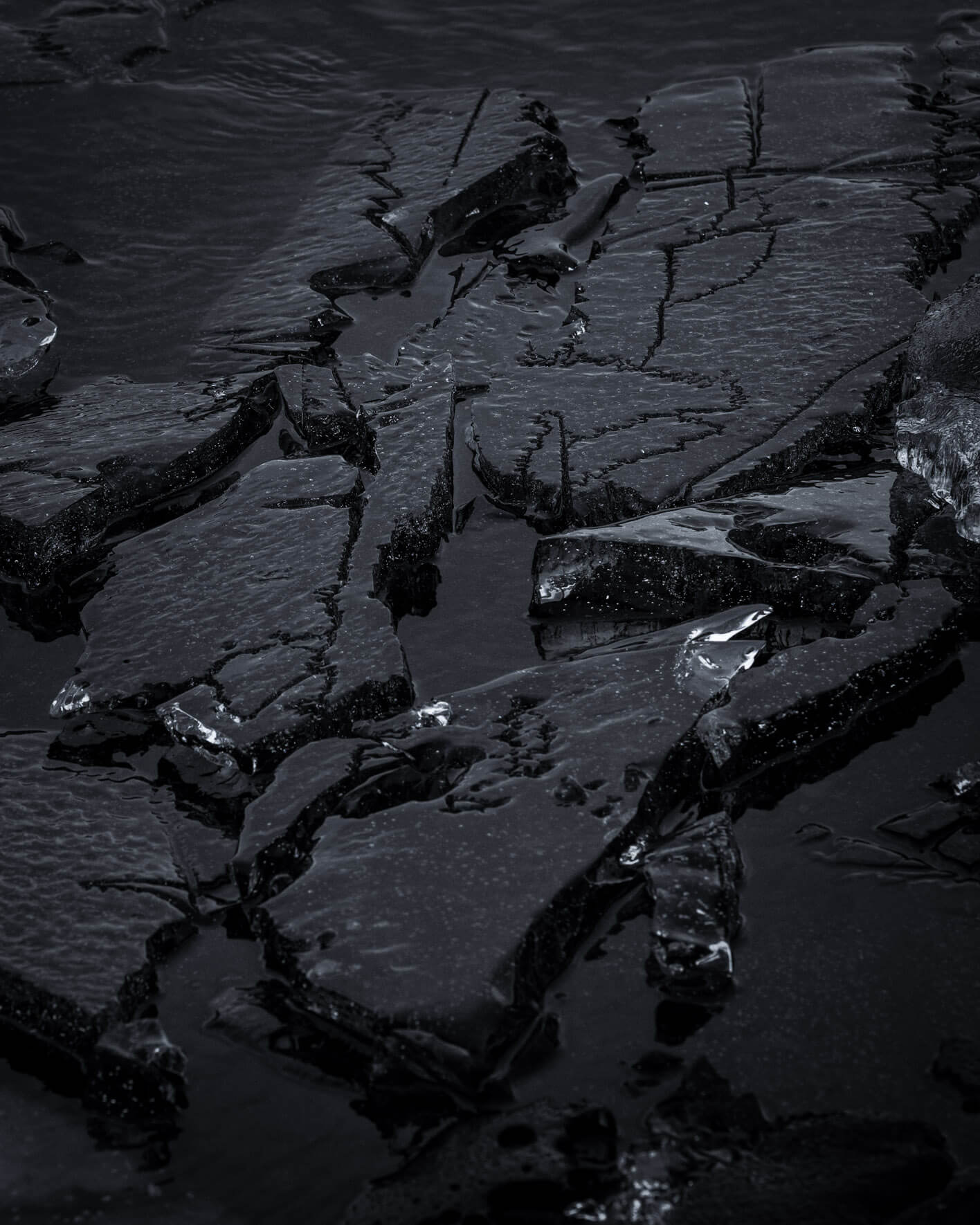 Detailed view of cracked dark ice on the shoreline of Lake Kleifarvatn in Iceland