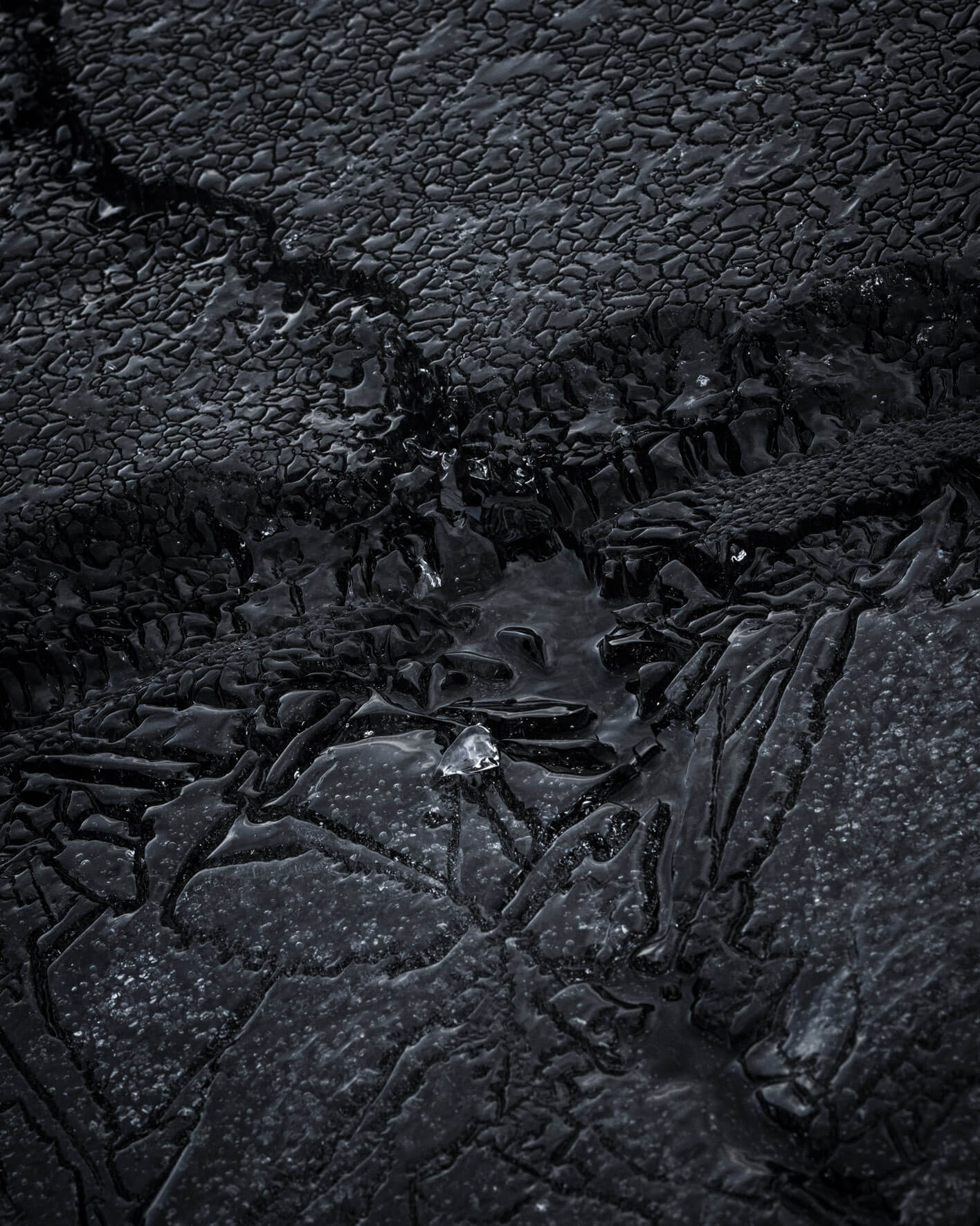 Cracked dark ice on the shores of Lake Kleifarvatn, forming striking natural patterns in Iceland