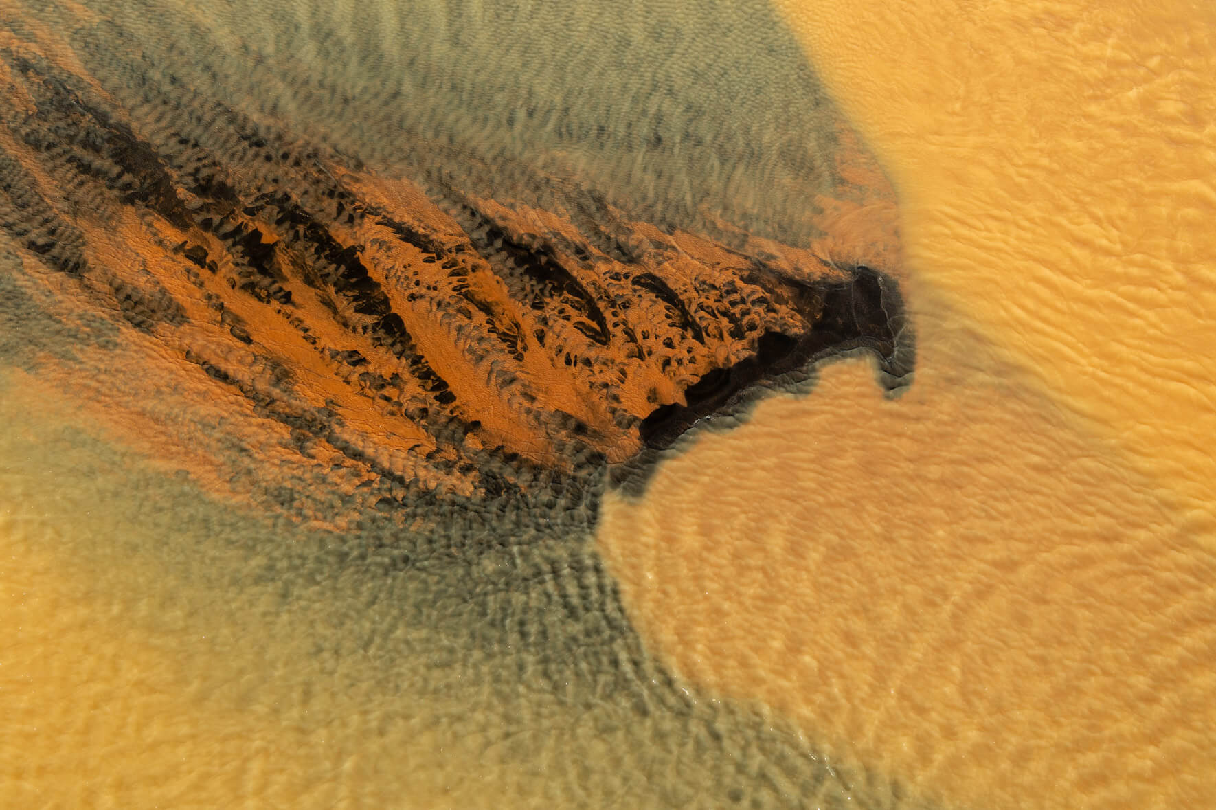 Aerial view of a sulphur-rich river in Iceland, displaying vibrant yellow hues due to geothermal activity