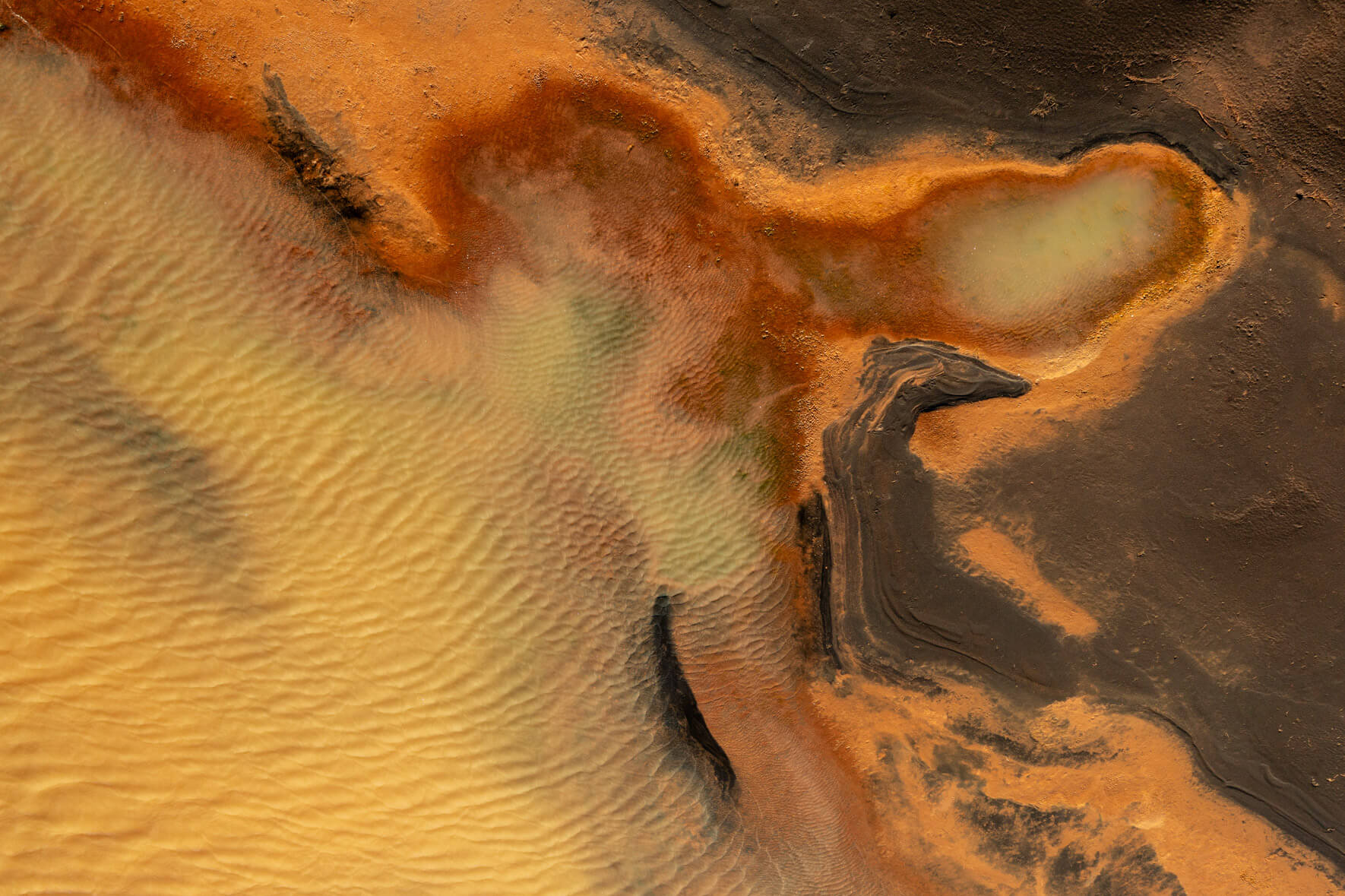 Drone image showcasing the contrast between dark volcanic sand and bright yellow sulphur-laden waters in Iceland