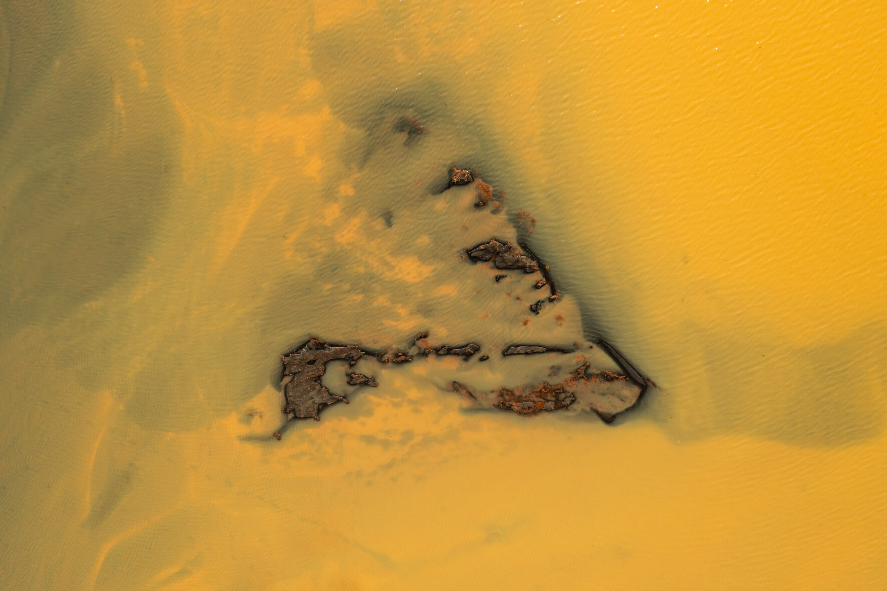 Aerial view of a sulphur-rich river in Iceland with a small sand island