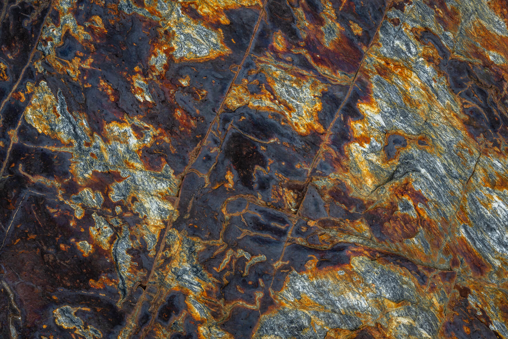 Close-up of weathered rock with copper and slate tones shaped by oxidation