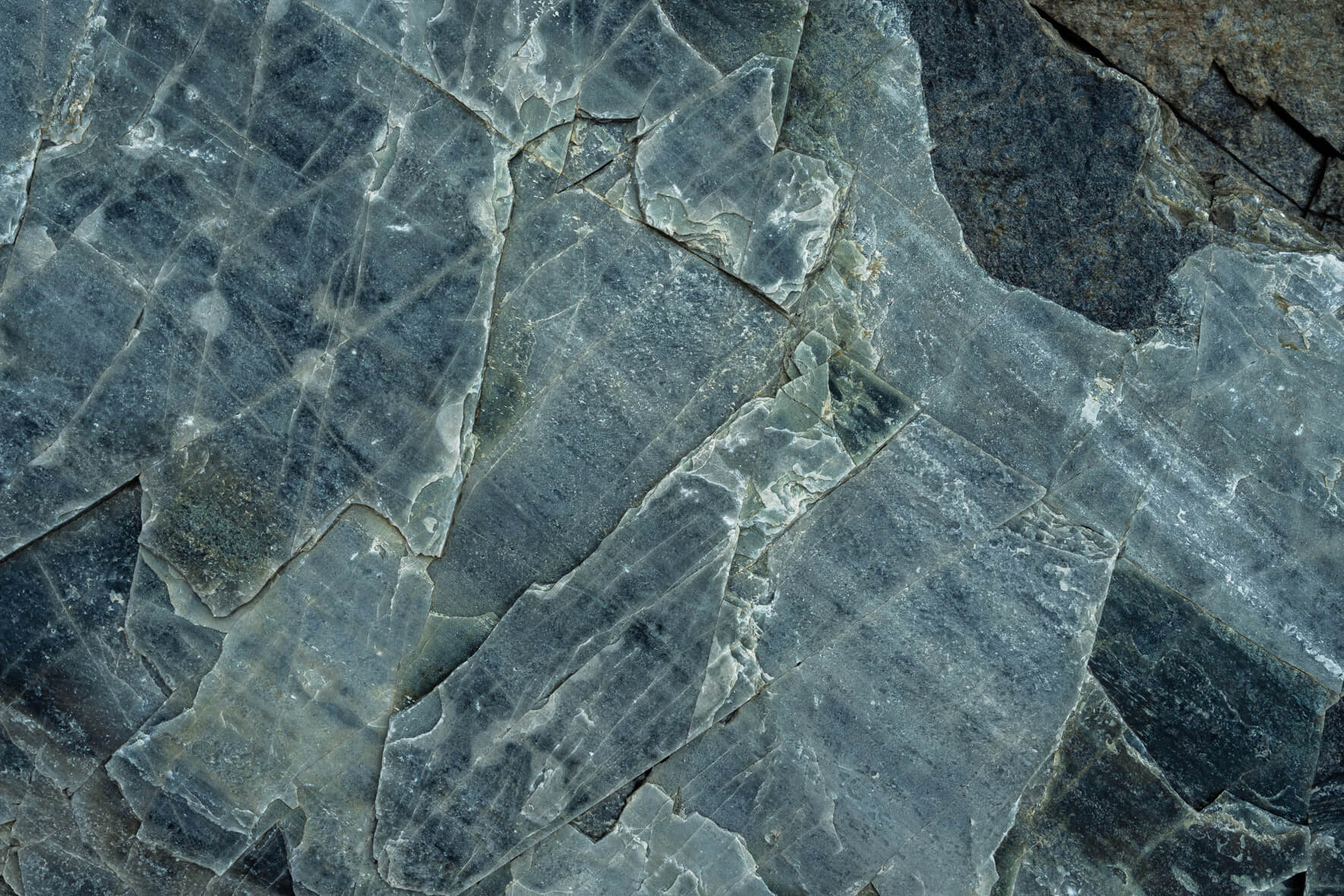 Oxidized rock face with copper and slate colors shaped by natural erosion