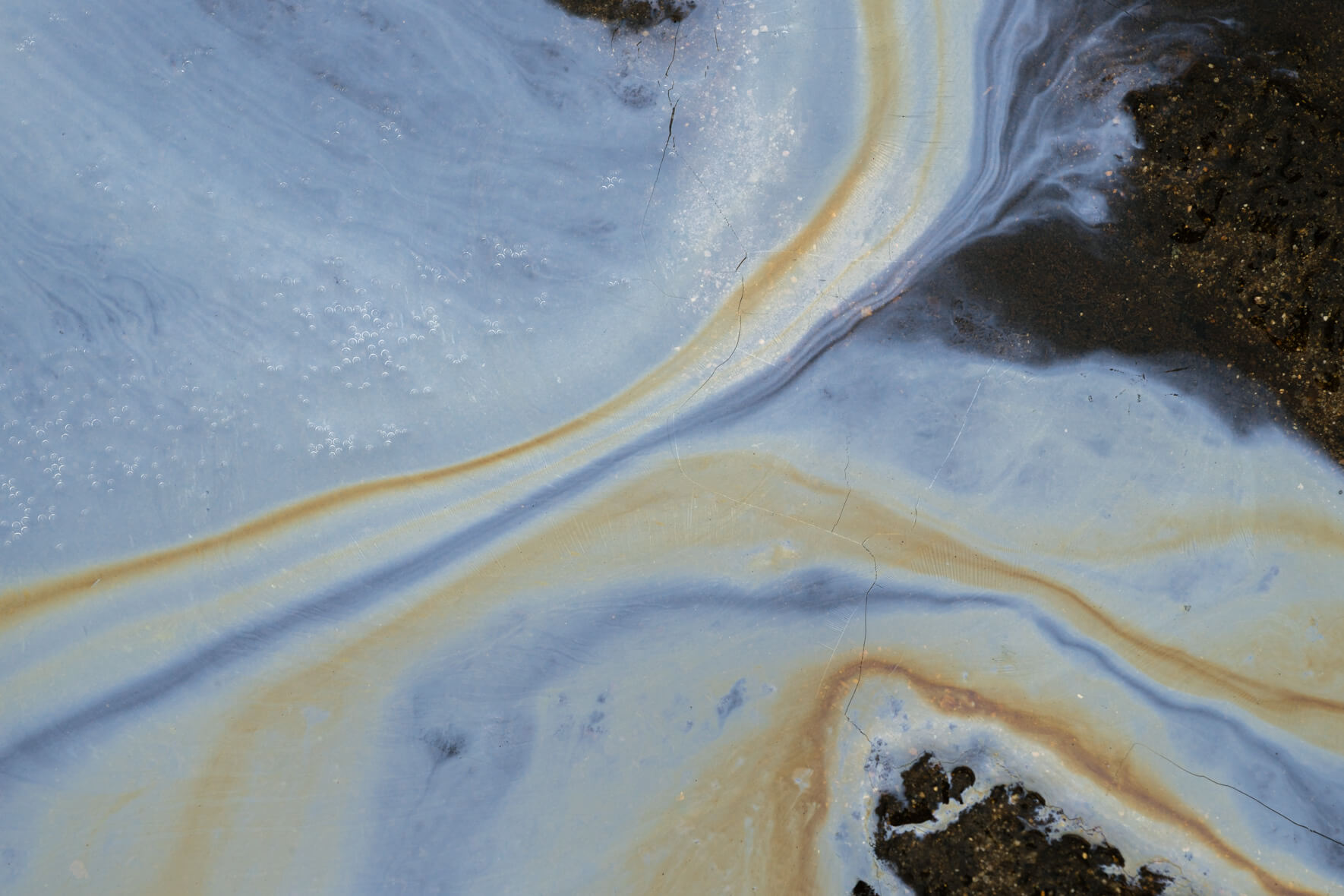Oxidized water surface in Norway with vivid orange and deep blue bacterial textures