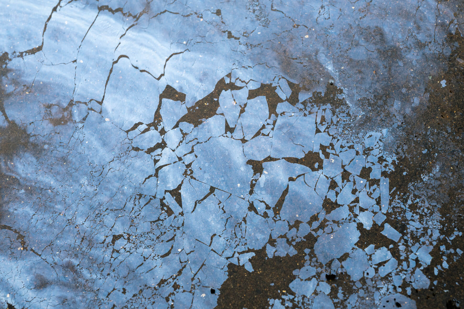 Surface texture of oxidized water showing fine cracks and deep iridescent reflections