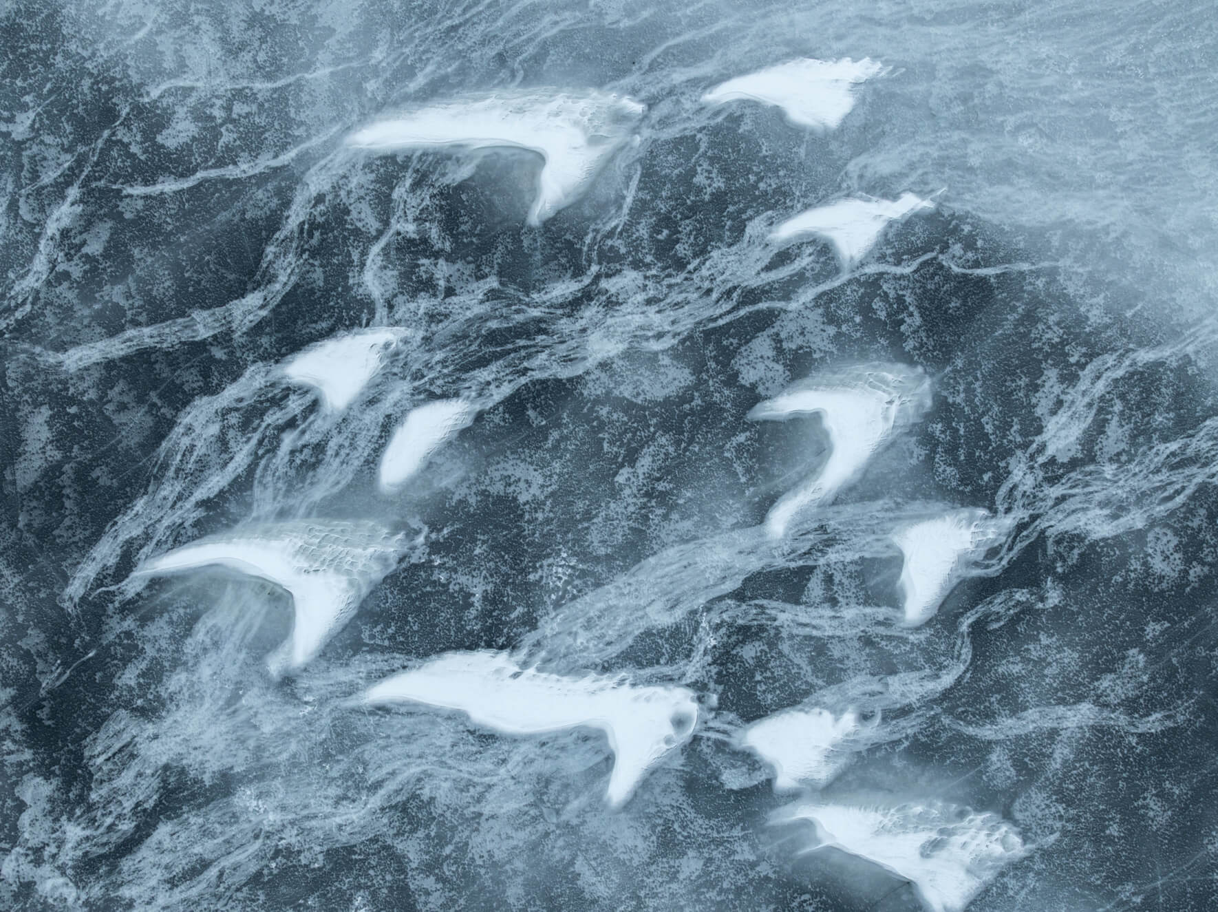 Abstract aerial of frozen lake surface combining snow wings and translucent ice tones