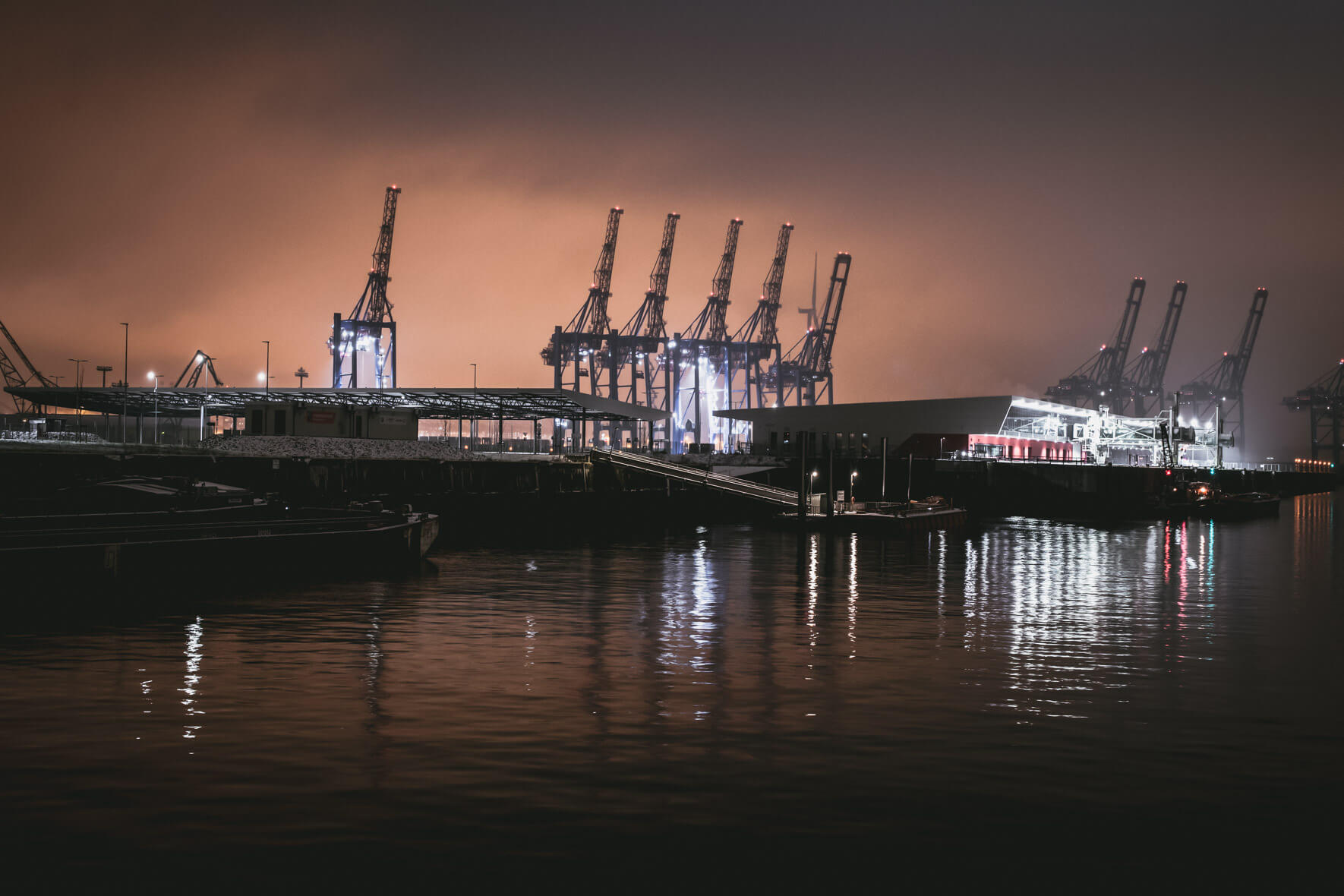 City lights over harbor cranes in Hamburg at night