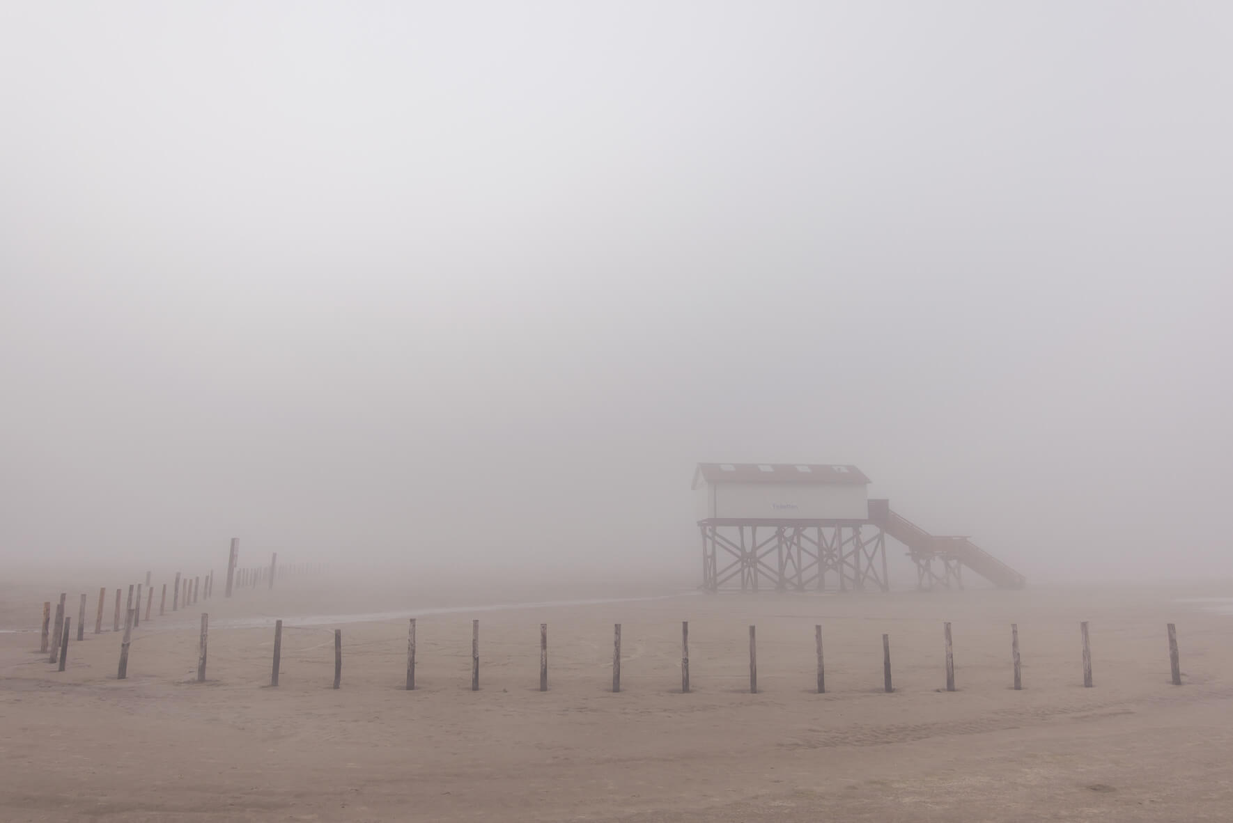 Coastal fog over the beach of Sankt Peter-Ording with a stilt house