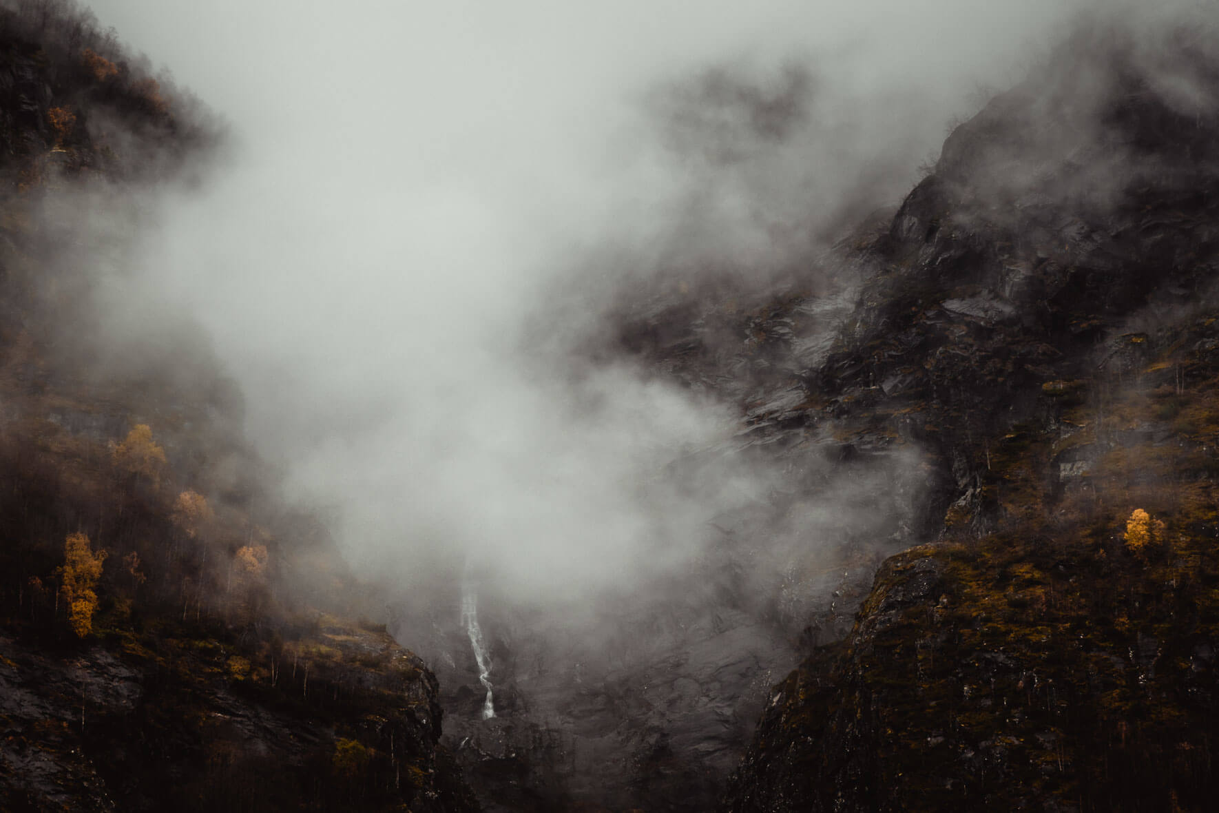 Moody autumn scene in Norway with clouds and waterfall